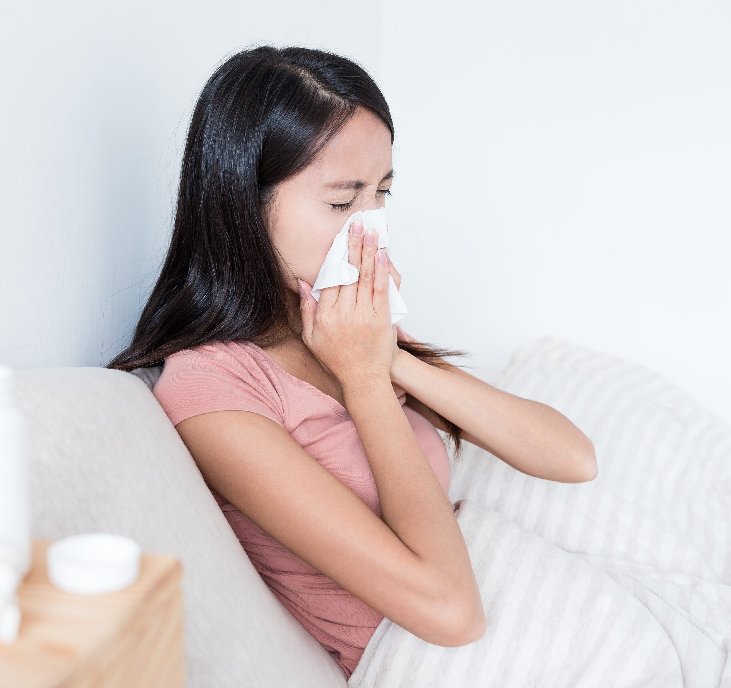 Image Woman sneezing on bed